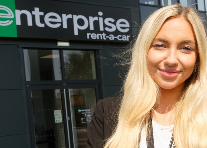 Selfie of female worker in front of Enterprise sign