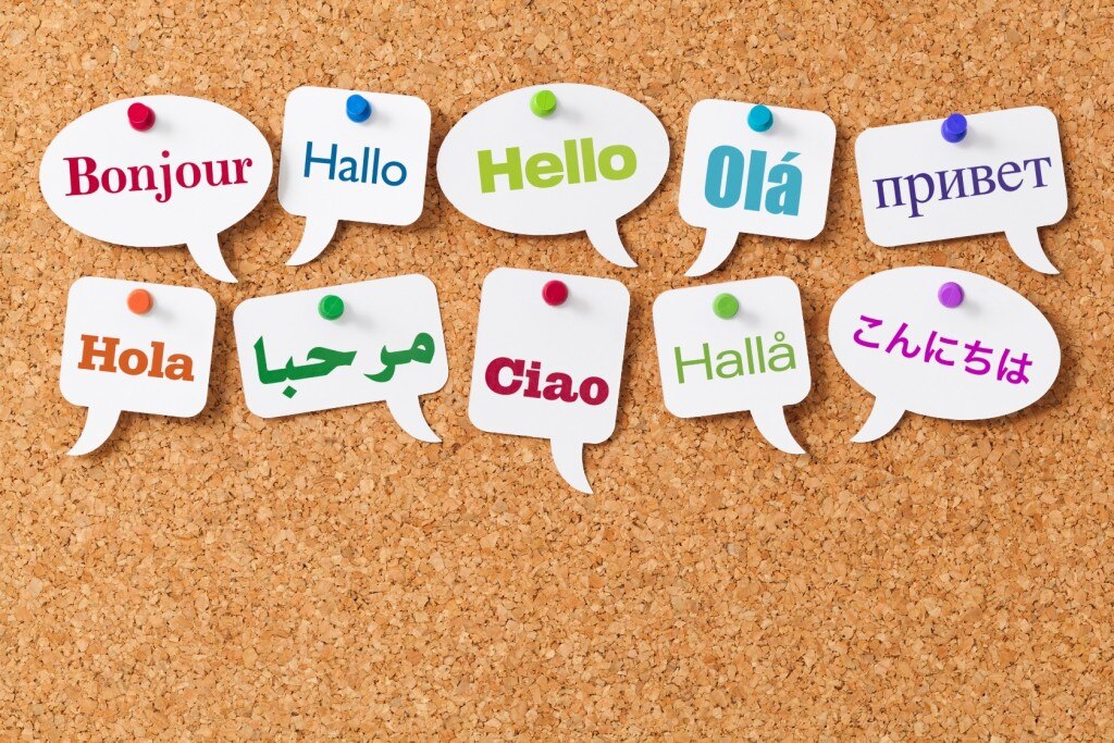 The word "Hello" in different languages on word bubbles pinned to a cork board
