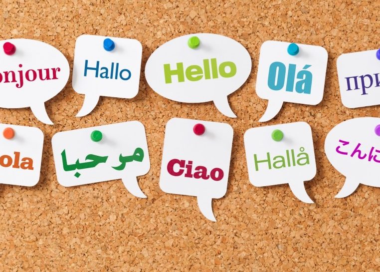 The word "Hello" in different languages on word bubbles pinned to a cork board