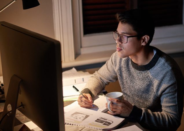 Student revising a paper late at night in the glow of a computer screen