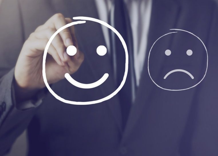 Man in suit drawing a smiley face and frowning face