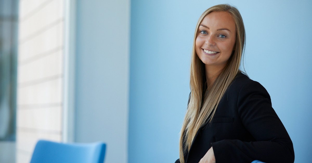 Female employee sitting in front of a blue wall