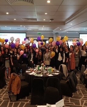 Employees at a celebration surrounded by balloons