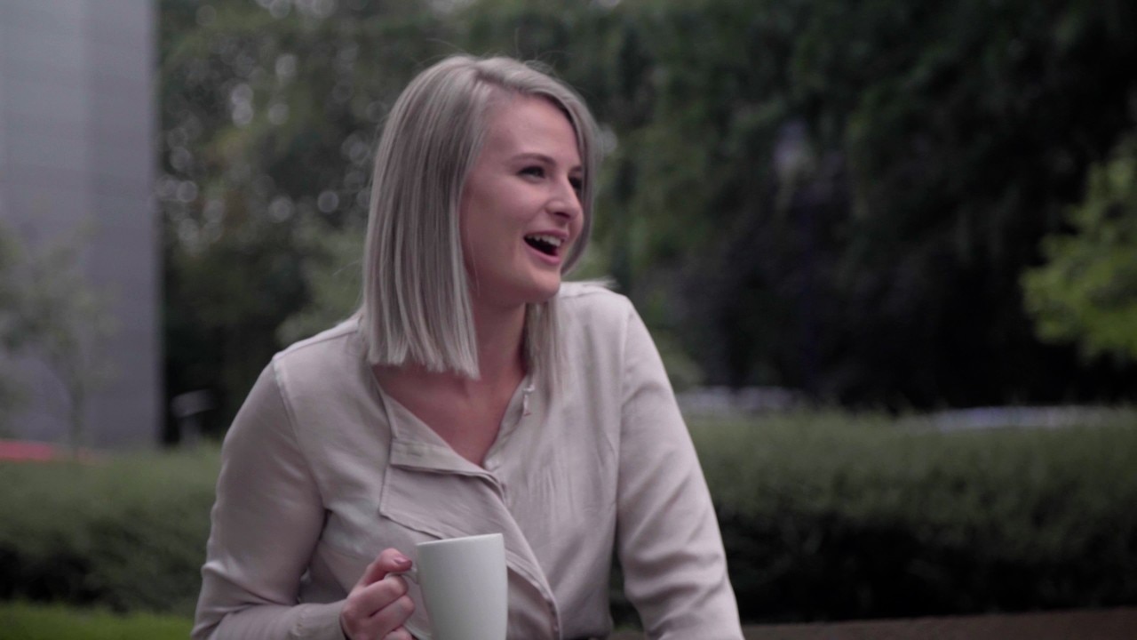 Enterprise Mobility team member in conversation while drinking from a mug.