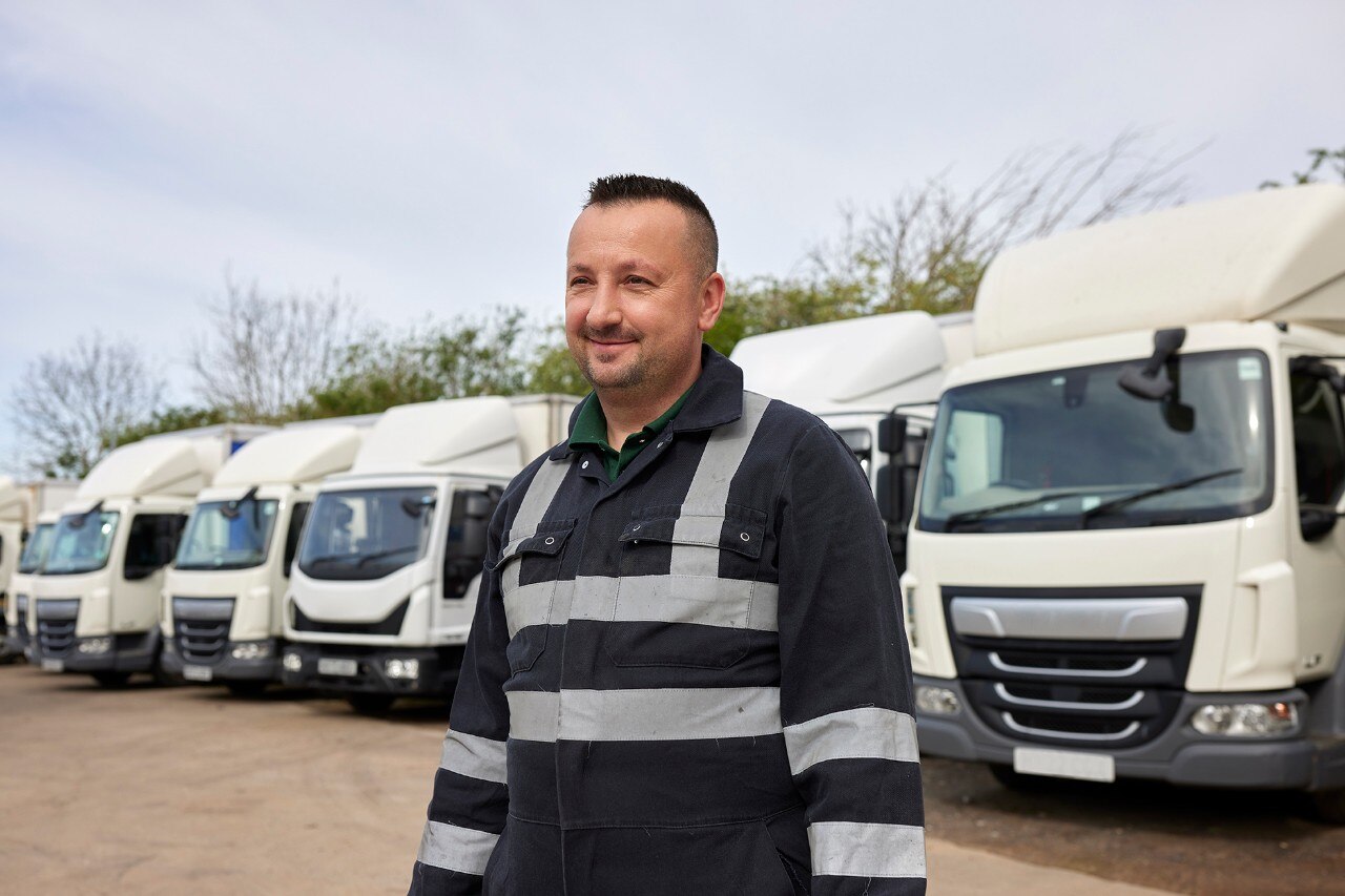 Enterprise Mobility team member smiling in front of a line of HGV trucks.