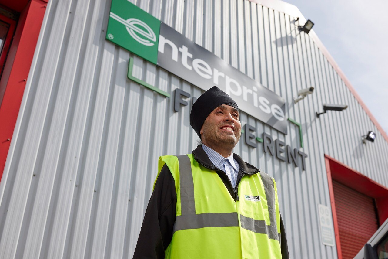 Enterprise Mobility team member in a high-visibility jacket standing outside a workshop entrance.