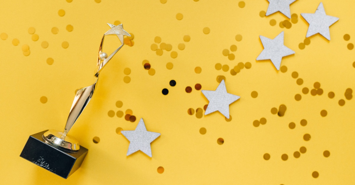 Trophy with glitter and stars scattered around on a yellow background