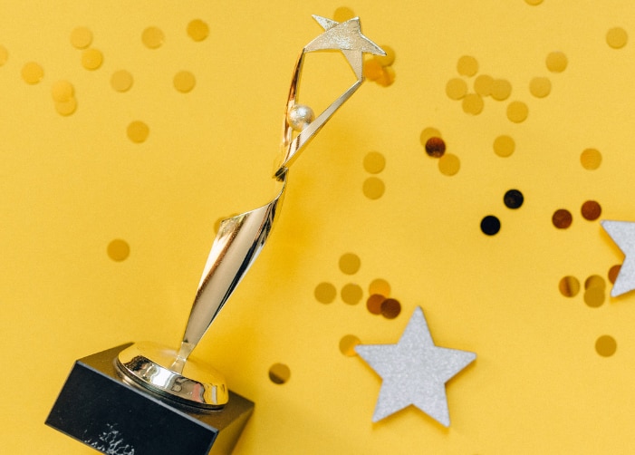Trophy with glitter and stars scattered around on a yellow background