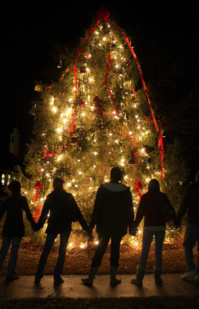 People holding hands in front of a Christmas tree