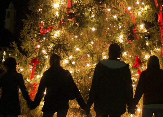 People holding hands in front of a Christmas tree
