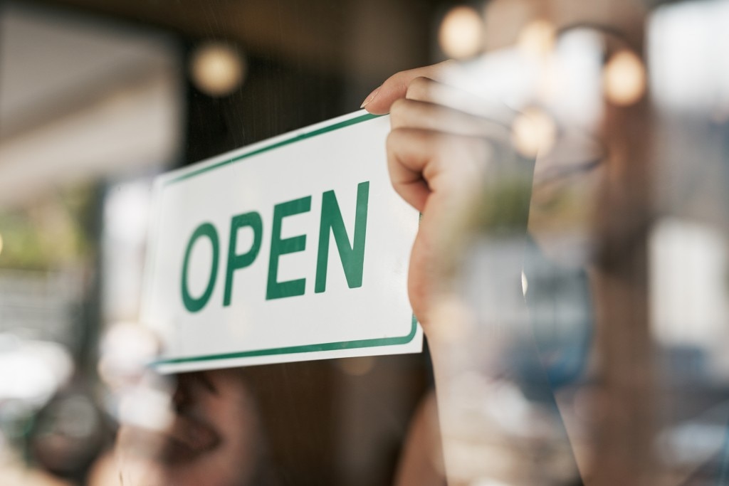 Hands flipping an "open" sign