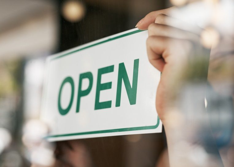 Hands flipping an "open" sign