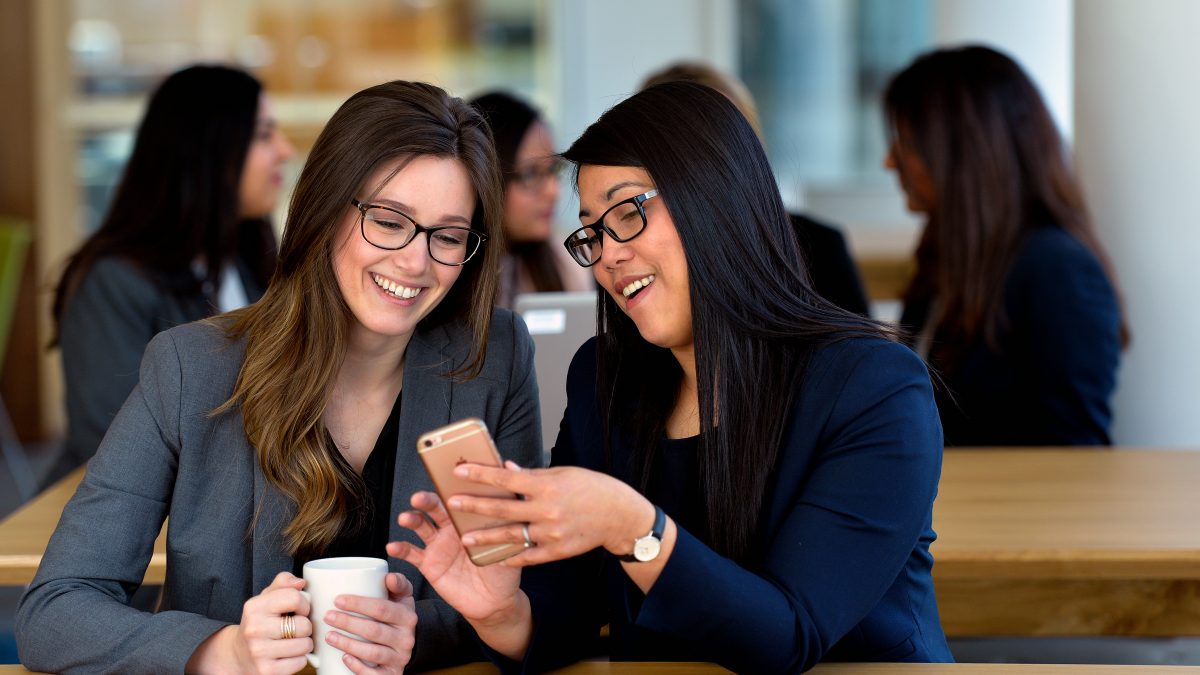 Two women smiling and looking at a cellphone