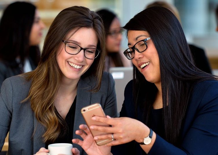 Two women smiling and looking at a cellphone