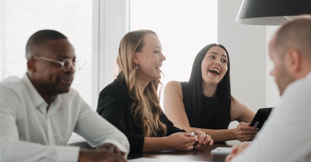 Interns sitting at a conference table while talking and laughing