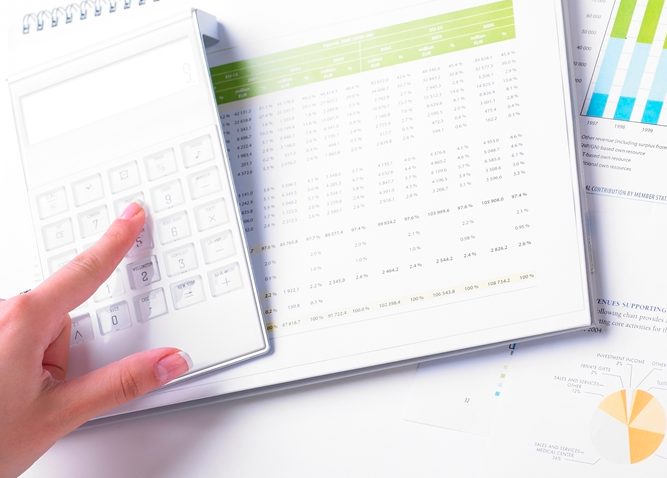 Finger using calculator while other hand holds a pen pointing to a graph