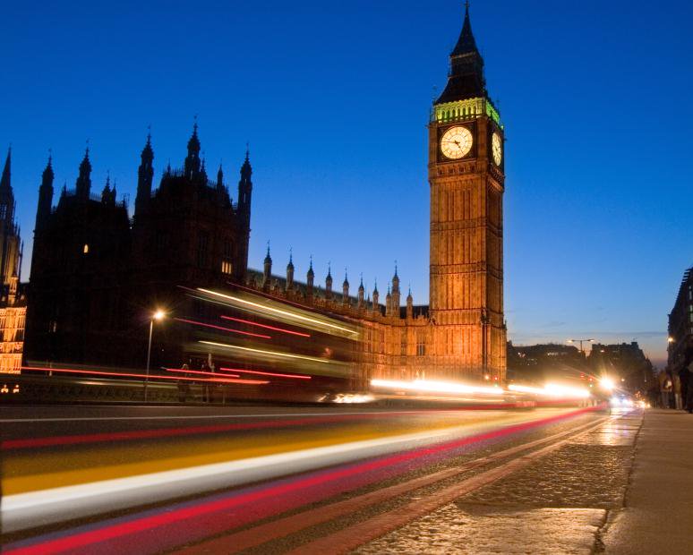 Headlights blurred on street in front of clock tower