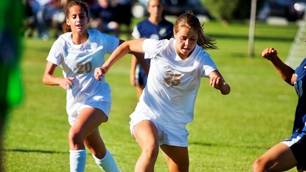 Girls playing soccer in white uniforms