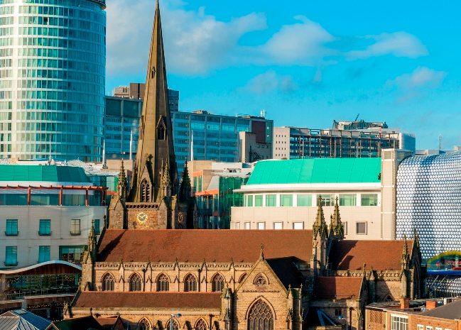 Photo of a city with a church and some interestingly shaped buildings