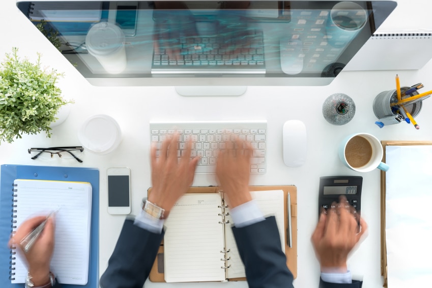 Hands blurry as they are multi-tasking at a desk