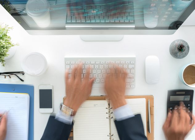 Hands blurry as they are multi-tasking at a desk