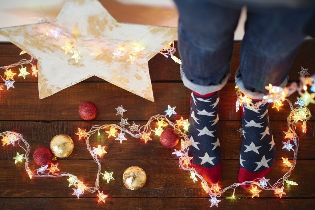 Feet in star socks surrounded by lights and ornaments for Christmas