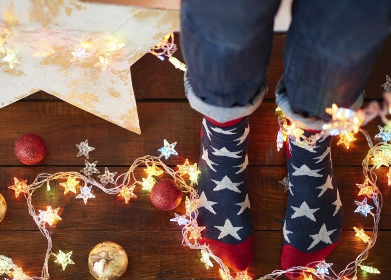 Feet in star socks surrounded by lights and ornaments for Christmas