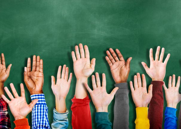 Hands raised in front of a chalk board background