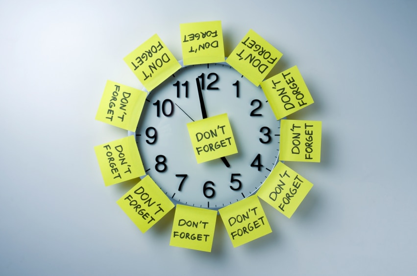 Clock covered in yellow sticky notes that say "Don't Forget"