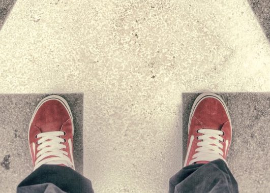 Feet standing across arrow painted on road