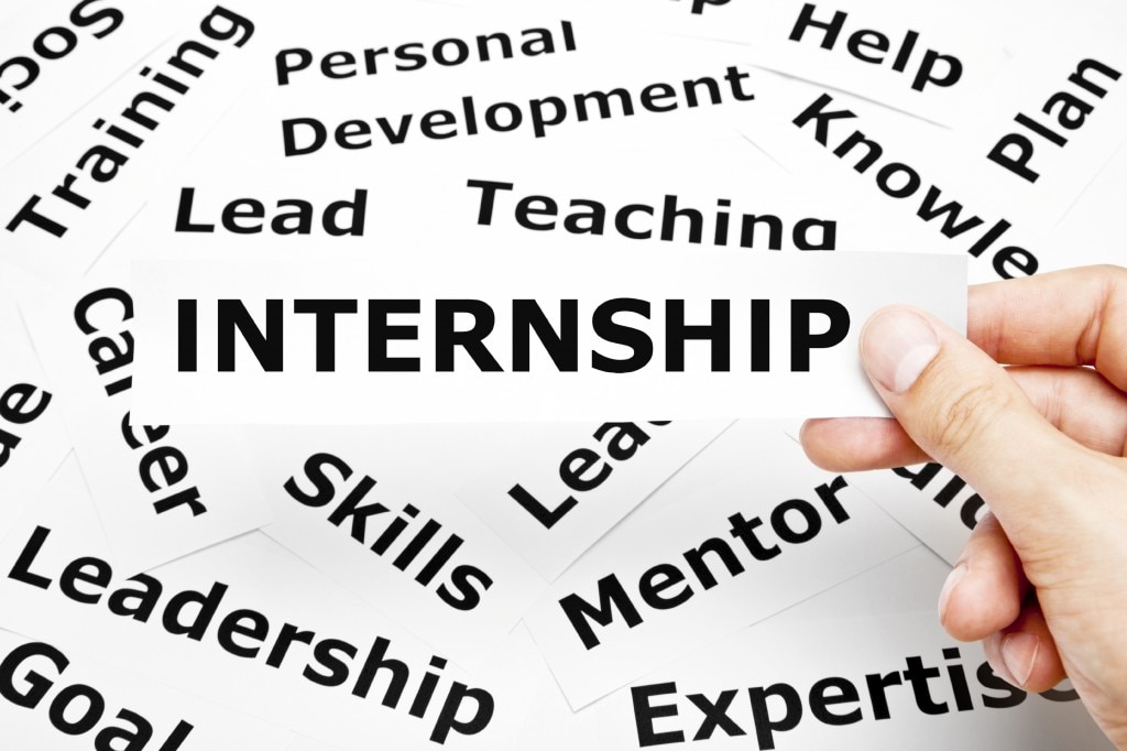 A pile of words you might find on a resume with a hand holding the piece that says "Internship"