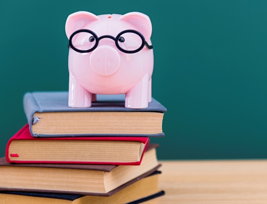 Piggy bank with glasses on top of pile of books