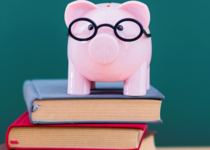 Piggy bank with glasses on top of pile of books