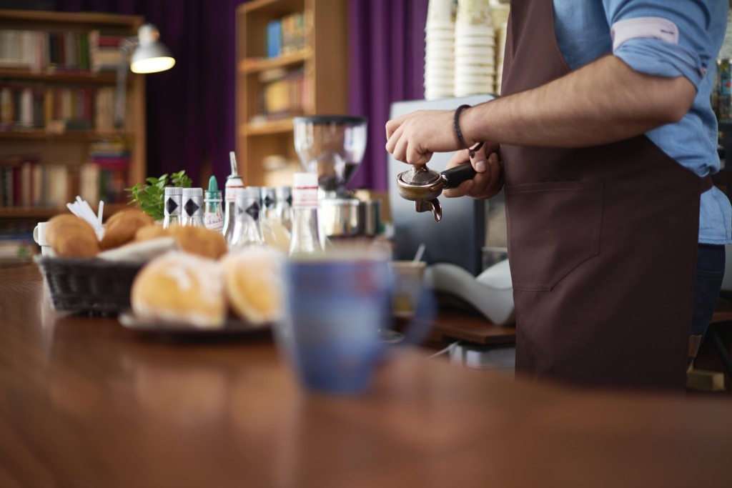 Person working as a barista in a coffee shop
