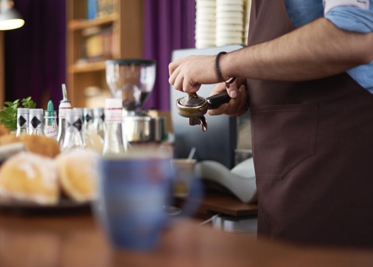 Person working as a barista in a coffee shop