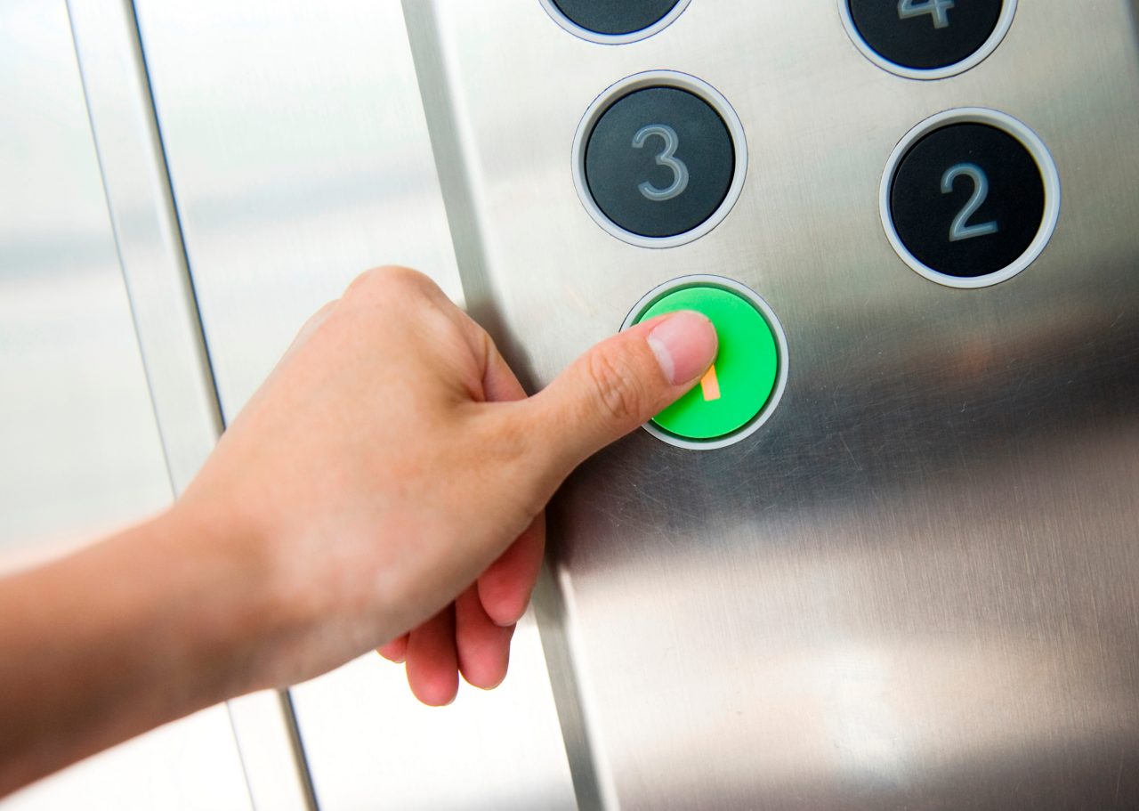 Thumb pressing the "1" button on an elevator