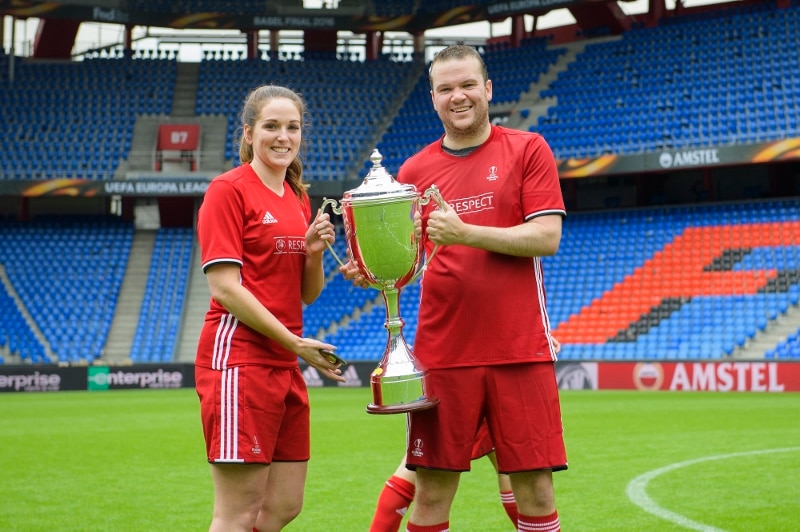 Two players in uniform holding a trophy