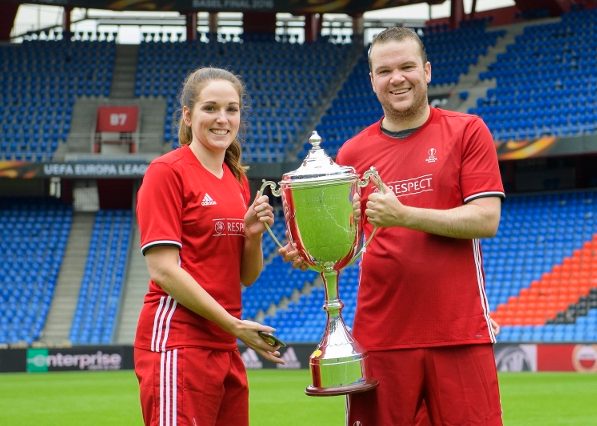 Two players in uniform holding a trophy