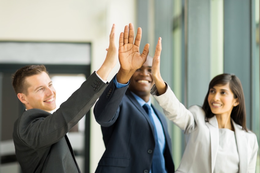 Three coworkers giving each other a high five