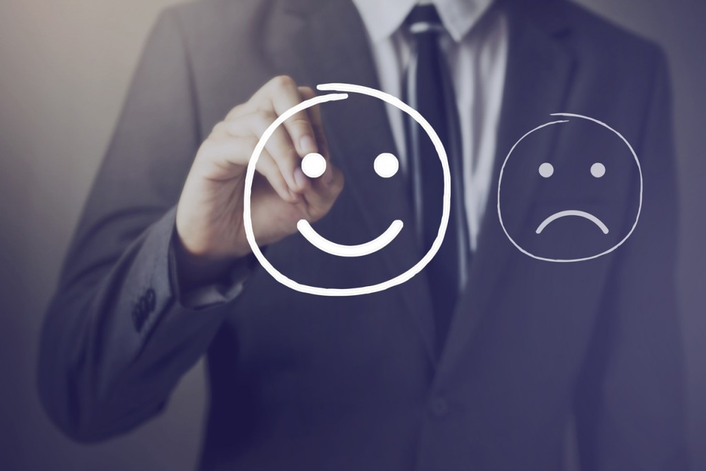 Man in suit drawing a smiley face and frowning face