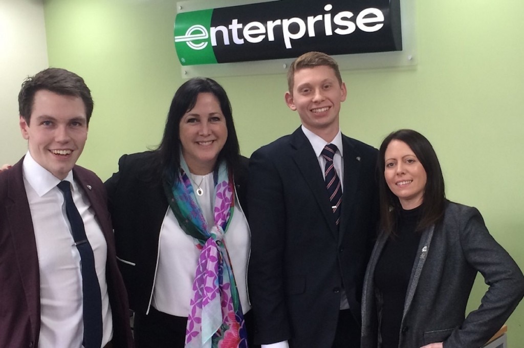 Four employees under Enterprise sign