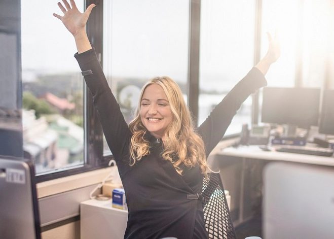 Ella throwing her hands up in excitement at her desk