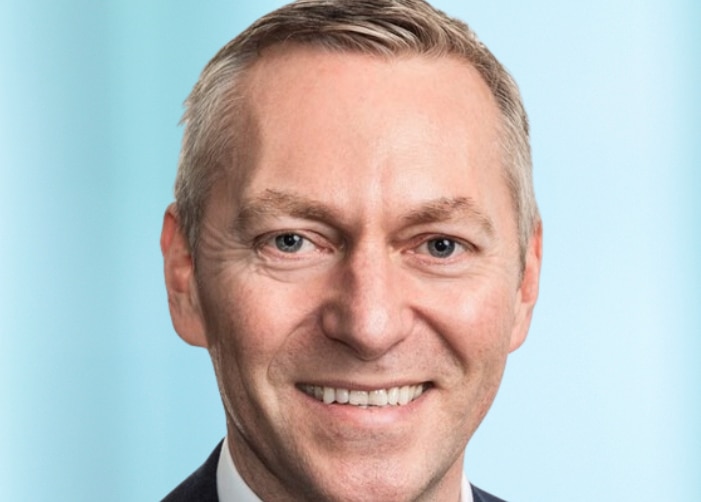 Paul McCorkell headshot on light blue background