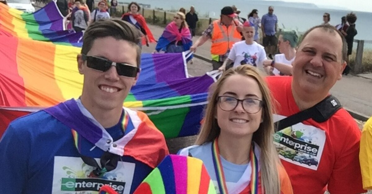Luke and other Enterprise Employees with the large PRIDE flag at a parade