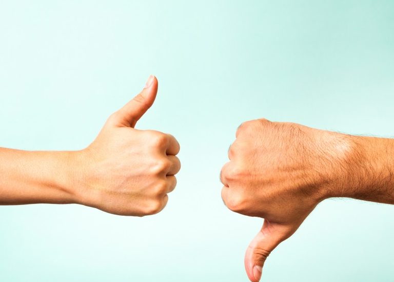Thumbs up and thumbs down on teal background
