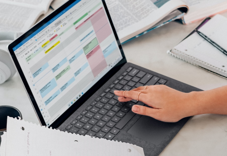 Hand typing on laptop with Outlook calendar open