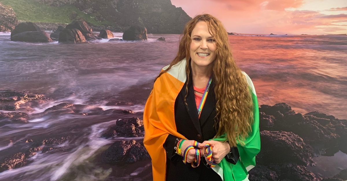 Leslee with Irish Flag around her shoulders in front of ocean
