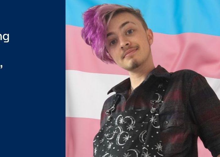 Picture of Jay in front of a blue, pink, and white flag with quote on blue background