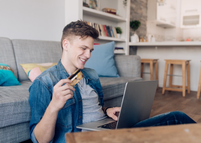 Student making money on laptop and holding a credit card