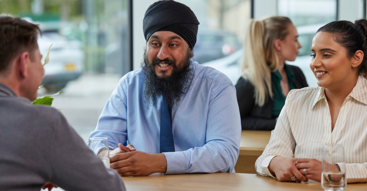 Three Enterprise Mobility team members sitting down at a table networking